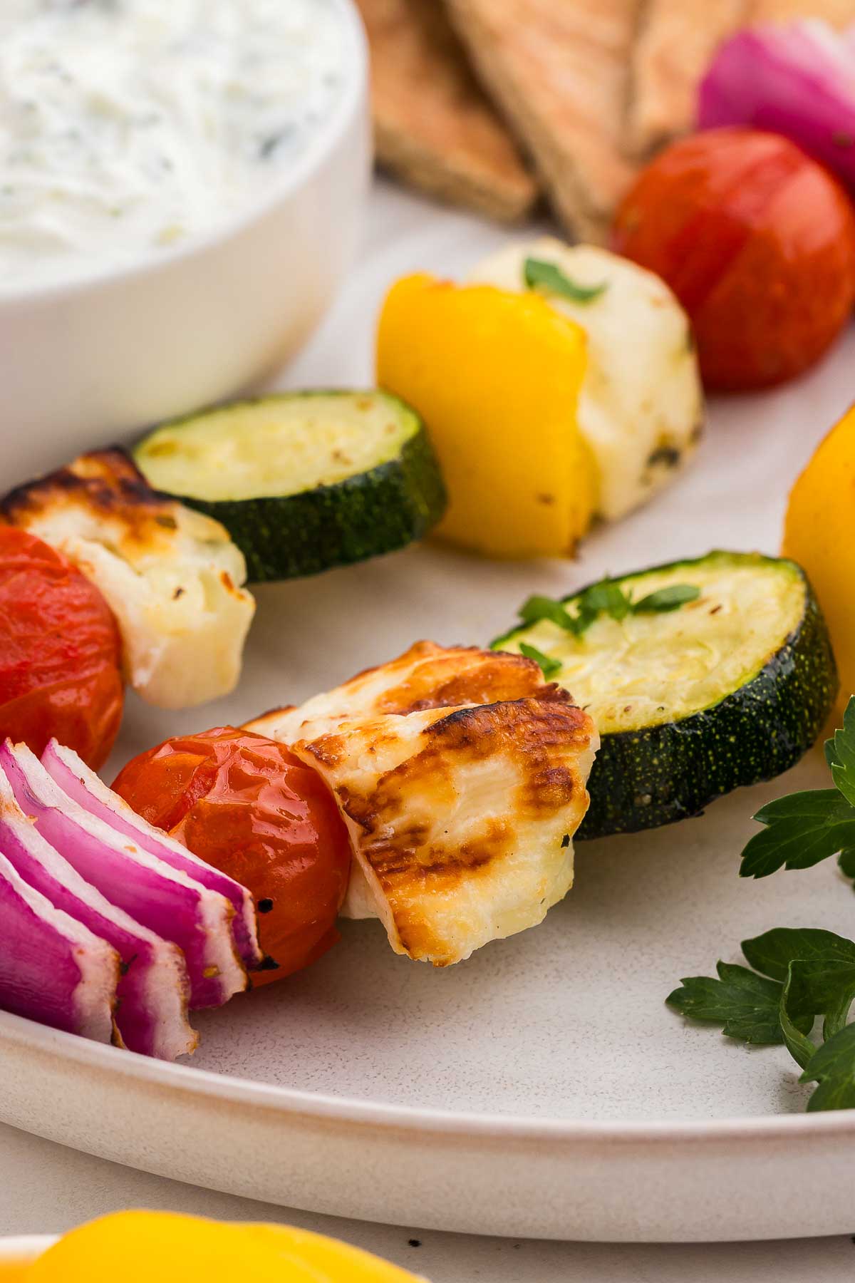 A close-up of halloumi and vegetable skewers with fresh parsley