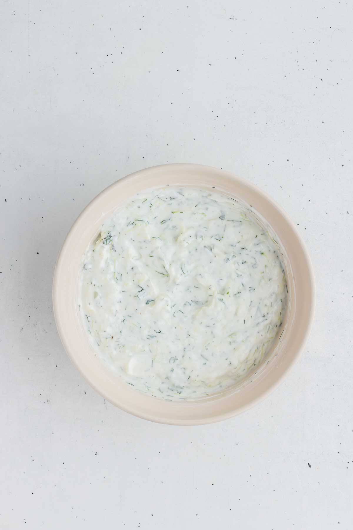 a white bowl with tzatziki sauce in it - overhead shot