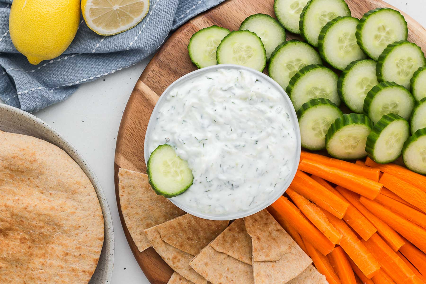 A bowl of tzatziki surrounded by veggies
