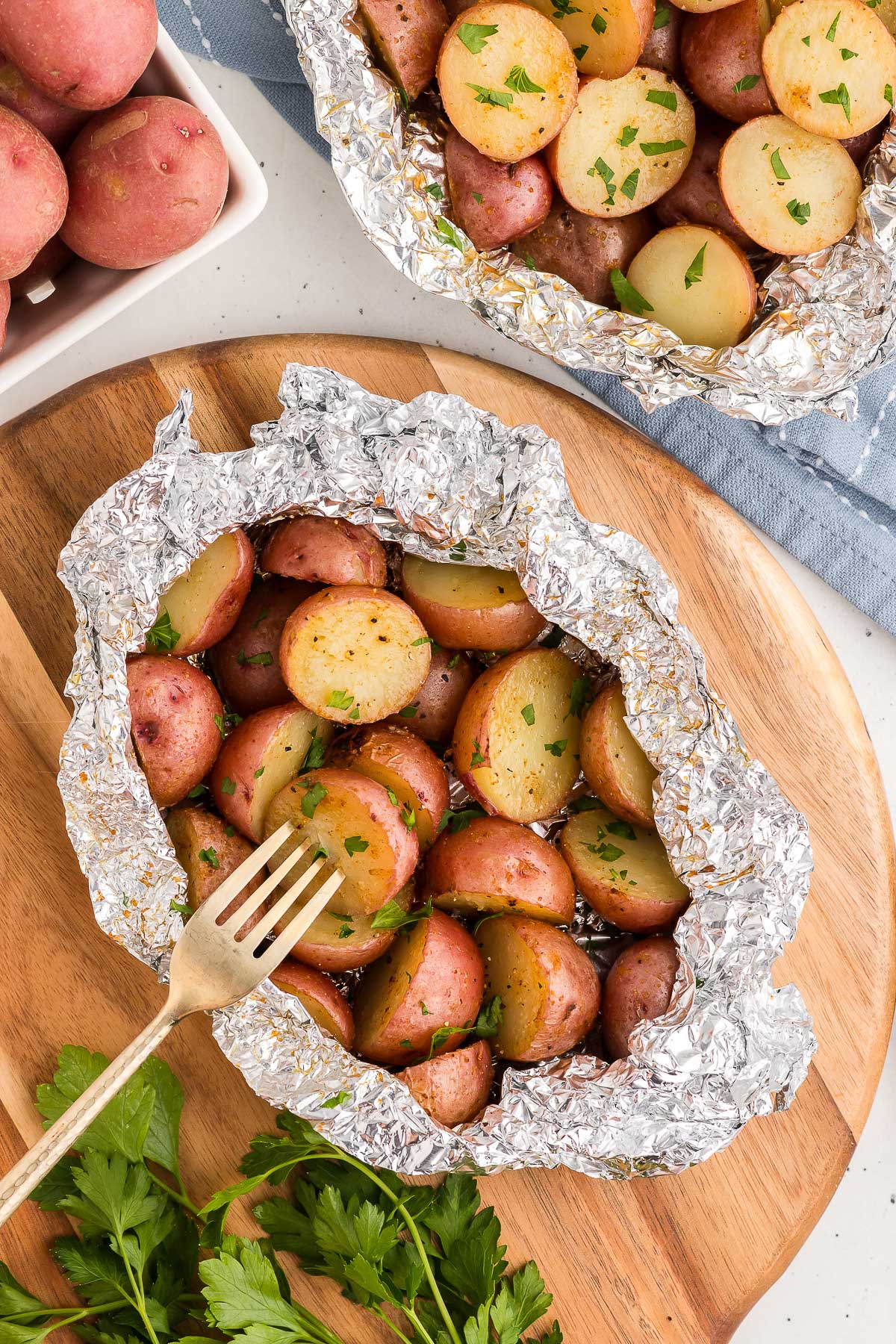 A fork inserted into a grilled potato that was grilled in a foil packet.