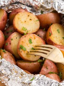 a fork inserted into a grilled potato in foil