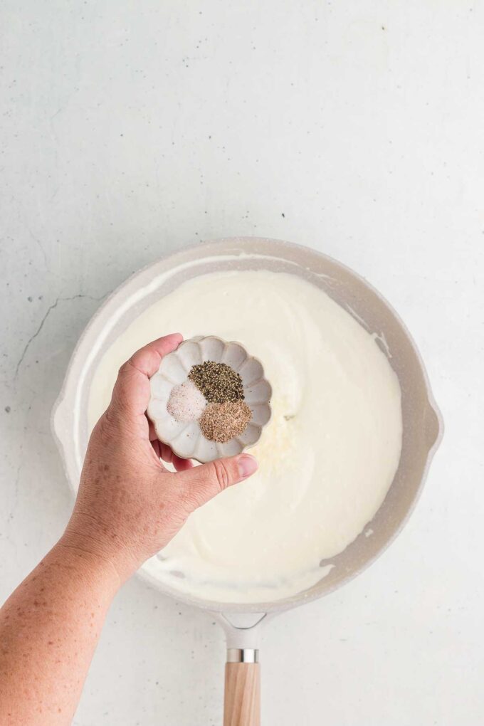 adding spices to Cream Cheese Pasta Sauce