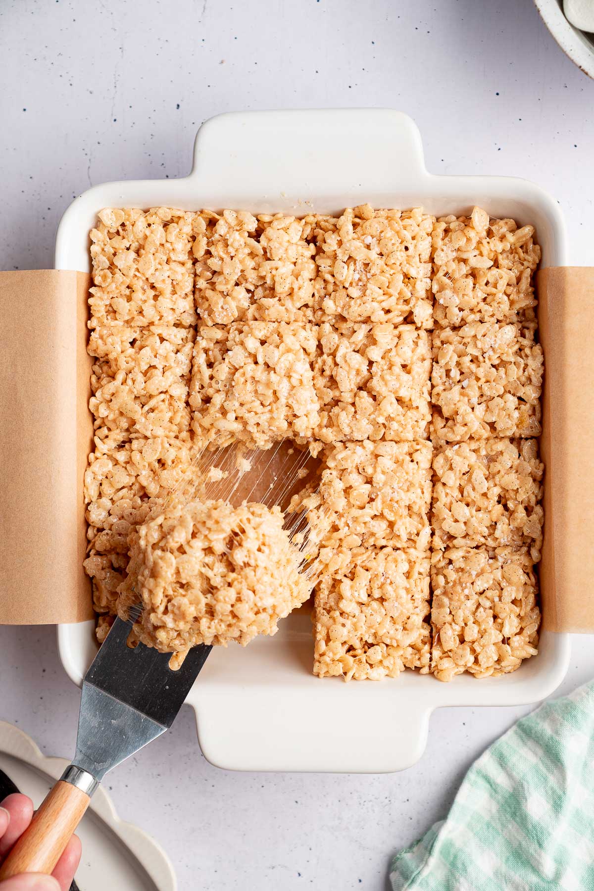 lifting a brown butter Rice Krispie treat out of the pan