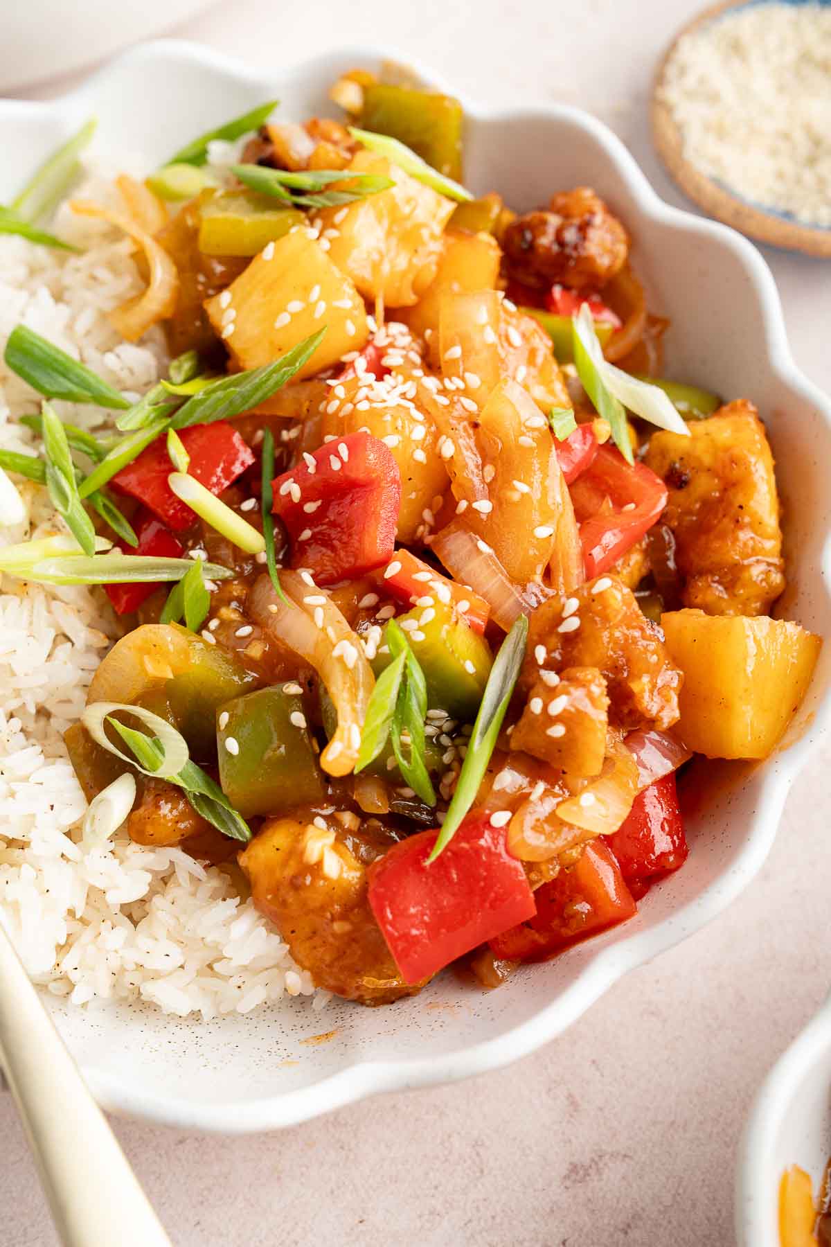 white bowl full of sweet and sour tofu with a fork in a white bowl